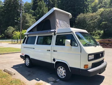 A white van with an open roof on the road.