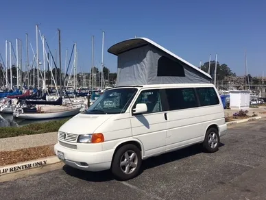 A white van parked in the street with a tent on top.