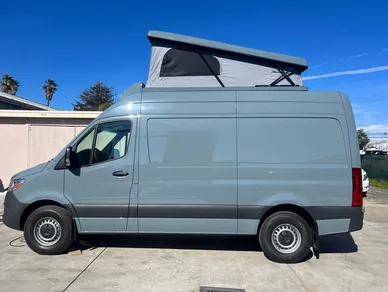 A van with an open roof is parked in the driveway.