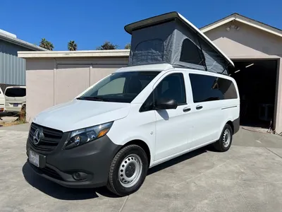 A white van with an open roof is parked in the driveway.