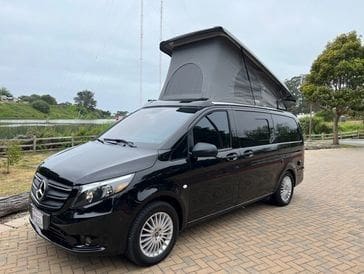 A black van with an open roof on the road.