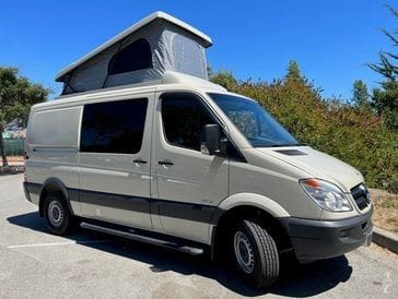 A van with an open roof is parked in the parking lot.