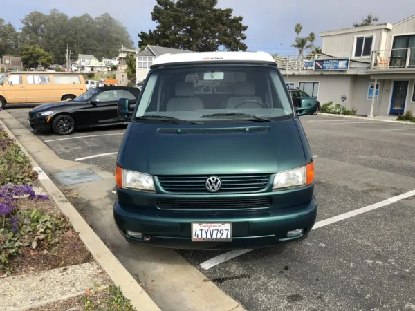 A green van parked in the parking lot of a building.