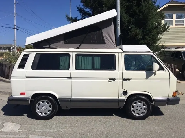 A white van with an open roof on the street.