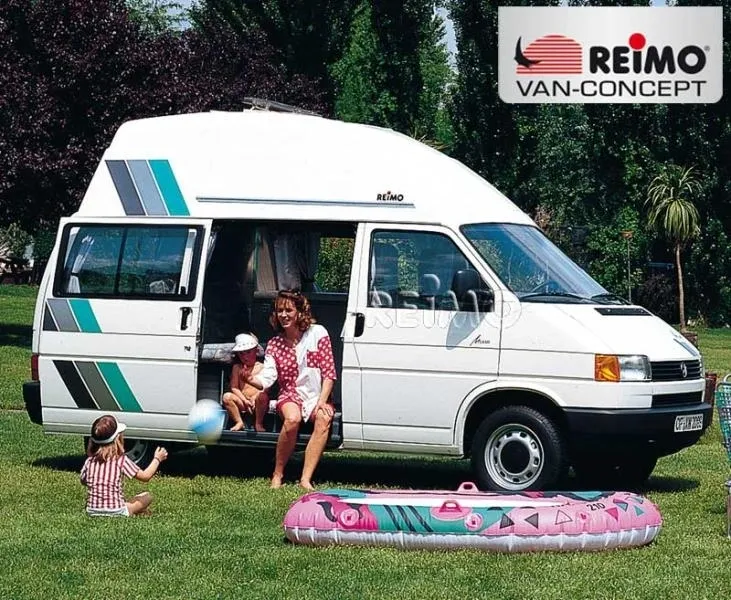 A van with people sitting in it and a child laying on the ground.