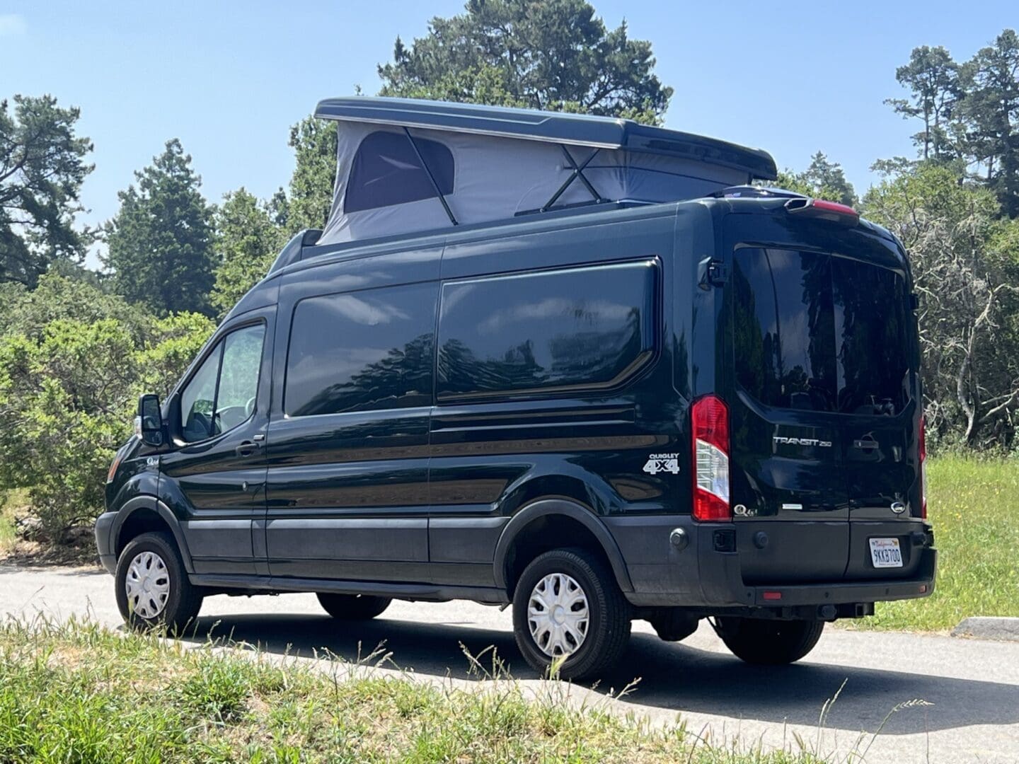 A black van with an open roof on the road.